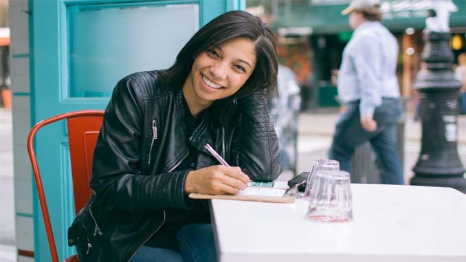 Young Woman Writing In Her Journal At An Outdoor Café