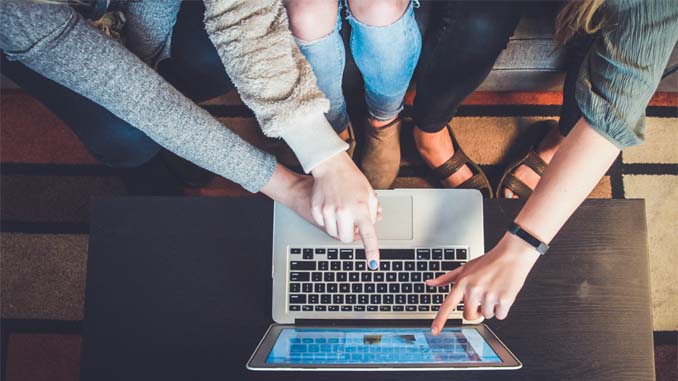 Three People Pointing At A Laptop Screen