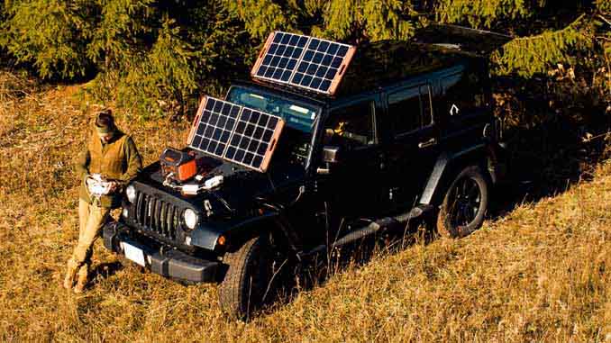 Man In The Wilderness With Solar Panels Connected To His Jeep