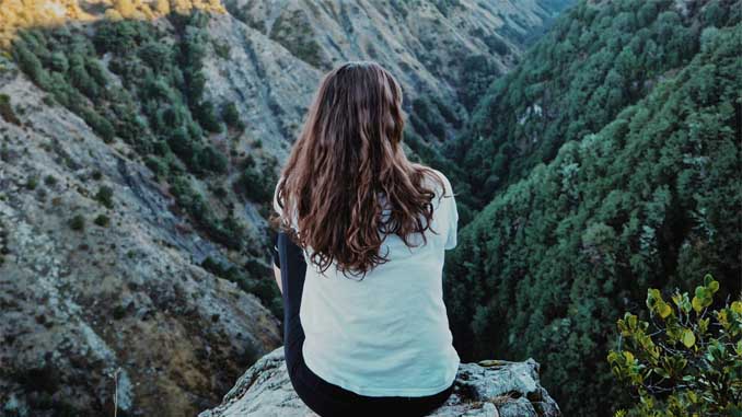 Woman Sitting On A Cliff In The Wilderness