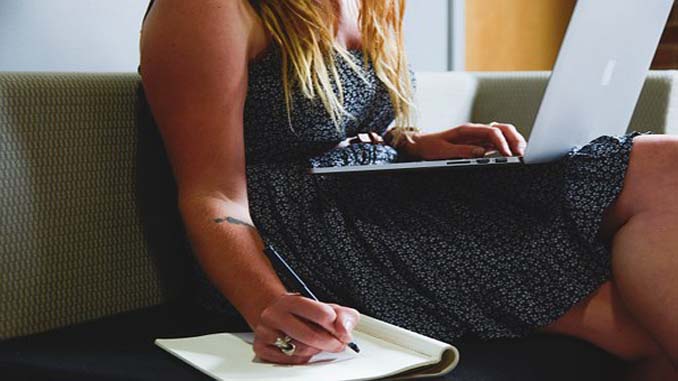 Woman On Couch With Laptop And Taking Notes