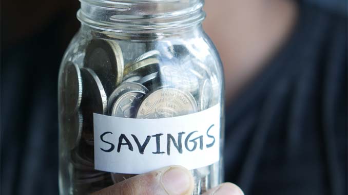 A Jar Filled With Coins With The Label "Savings"