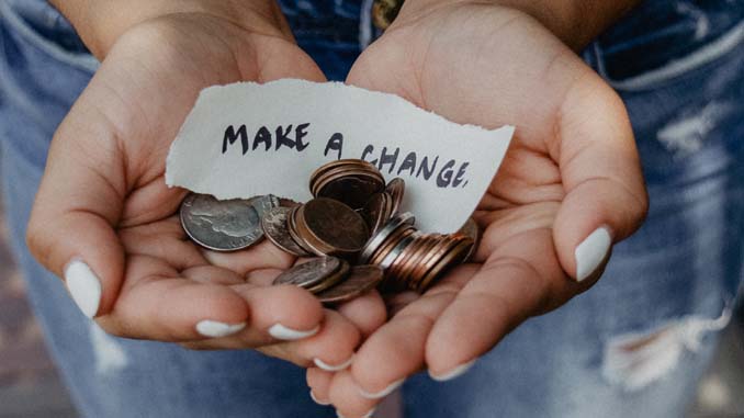 Hands Holding Coins And A Note Reading "Make A Change"