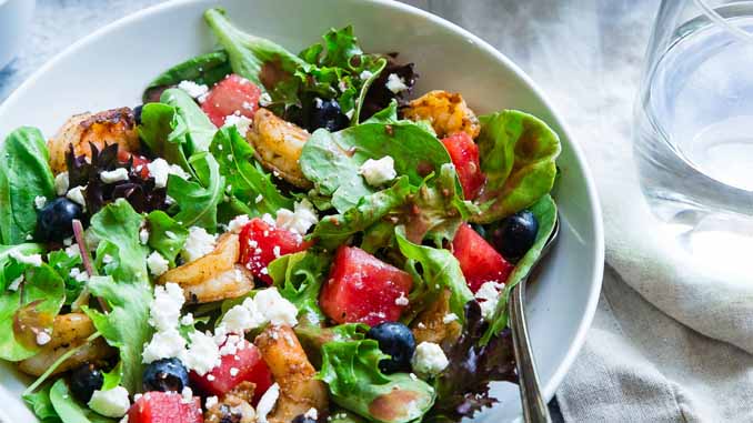 A Bowl Of Salad With Berries, Spinach, Shrimp...