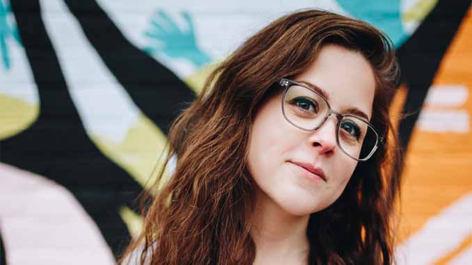 A Woman Standing In Front Of A Painted Wall