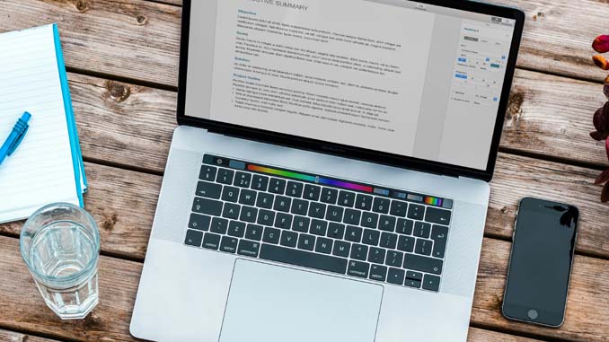 A Laptop, Cellphone, Glass Of Water And Notepad