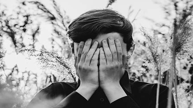 Man In Field With Head In His Hands