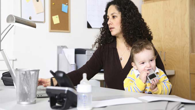 Woman At Her Laptop Holding Her Baby