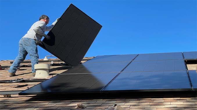 Man Installing Solar Panels On Roof