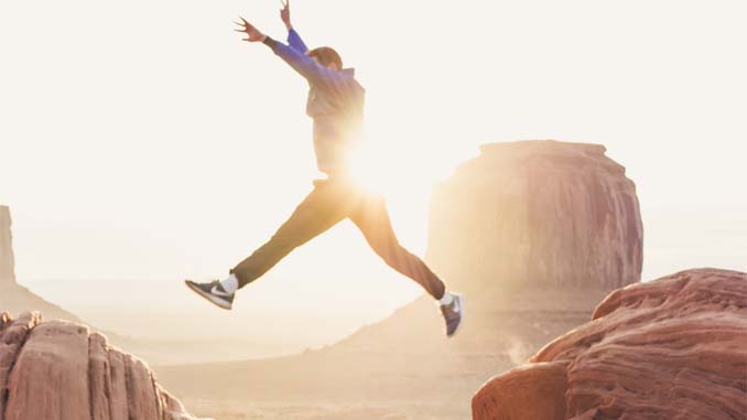 Man Jumping Across Rocks At Sunset