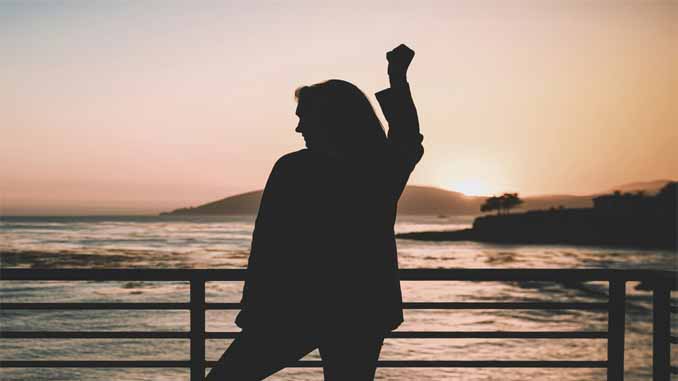 Woman At Sunset On The Pier Fist Pumping The Sky