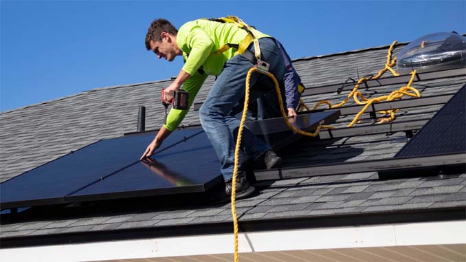 Man Installing Solar Panels On Roof