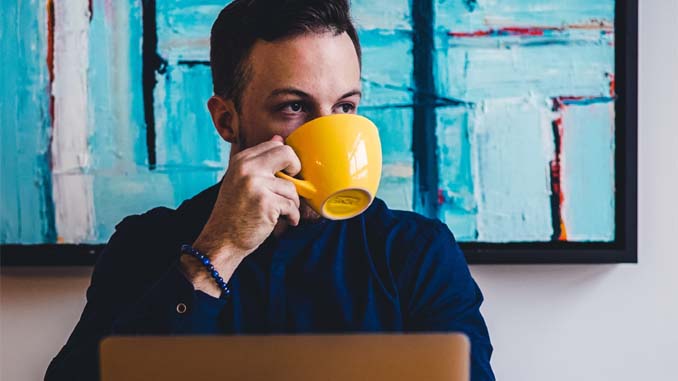Man Sipping Coffee At His Laptop