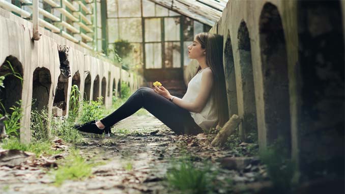 Young Woman Sitting With Her Back Against A Wall