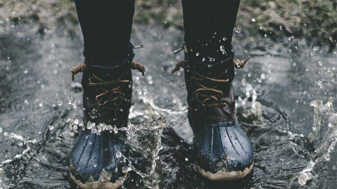 Person In Wellington Boots Standing In A Puddle On A Rainy Day