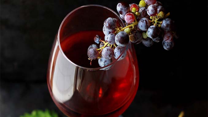 A Glass Of Wine With A Bunch Of Grapes On It