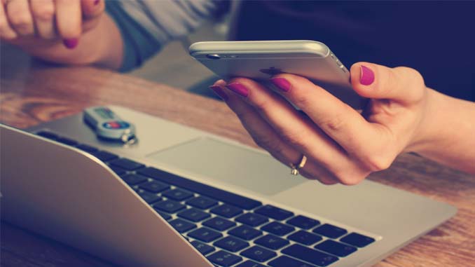 Woman At Laptop With Her Cellphone