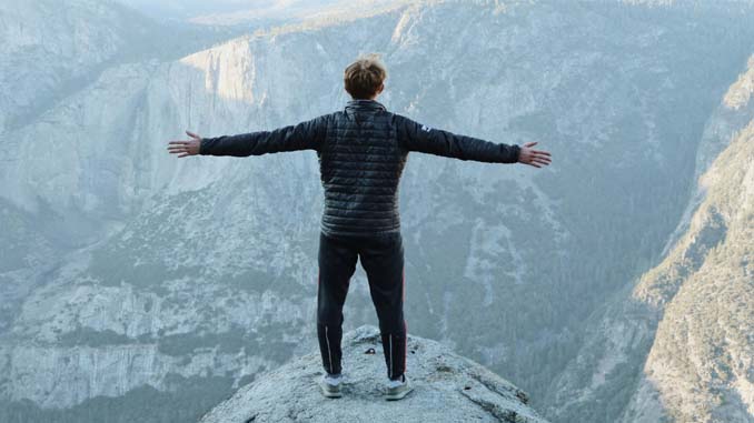 Man Standing On A Cliff With Outstretched Arms