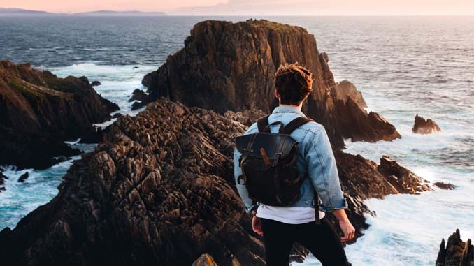 Man Standing On The Rocks Watching The Ocean