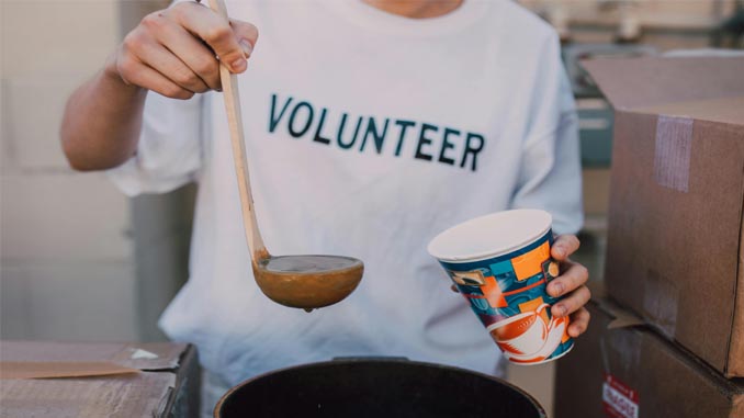 Volunteer Pouring Food Into A Cup