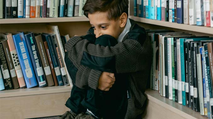 Young Boy Sitting Alone In A Corner